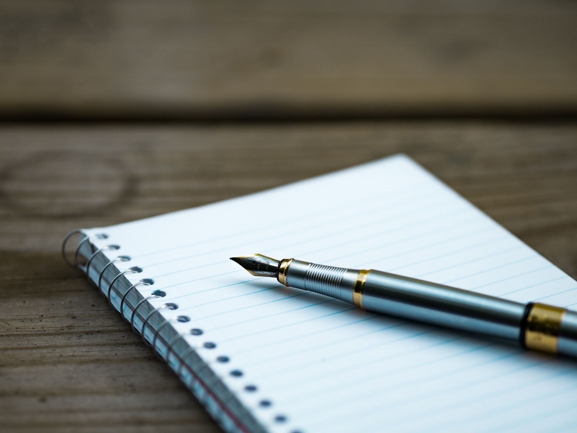 A fountain pen is placed on an empty notebook