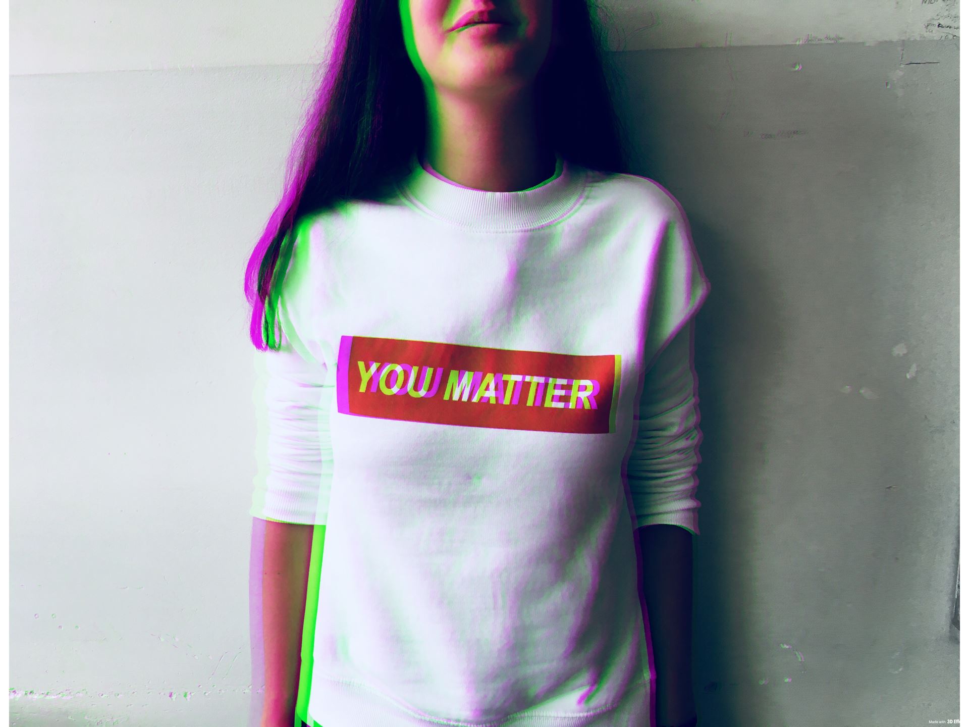 A person wears a white t-shirt with a red logo and white writing which spells out 'You matter'