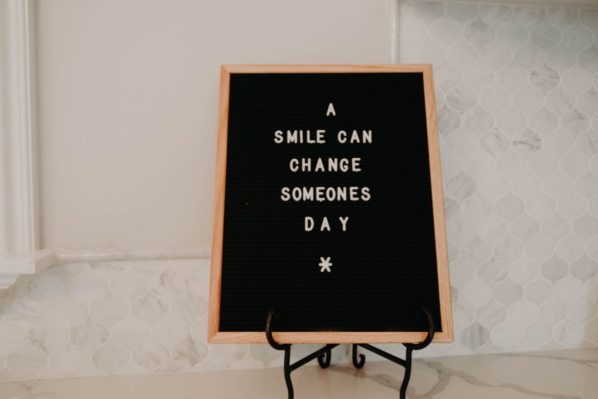 A black sign shows white lettering to read 'A smile can change someone's day'